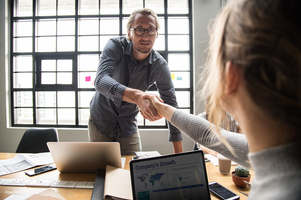 Two people shaking hands over a signed agreement