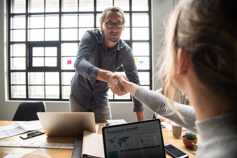 Two people shaking hands over a signed agreement